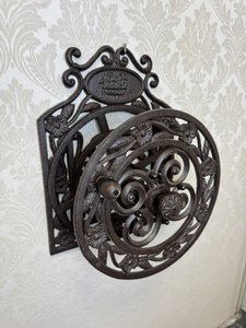 Litinový držák na zahradní hadici s květinovým dekorem a ozdobným nápisem