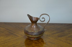 Měděný džbán s ladným křivkovým uchem a dekorativním reliéfem