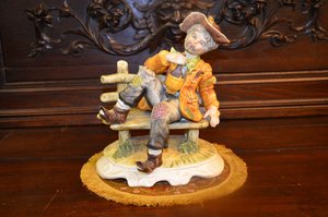 Porcelánová soška odpočívajícího hudebníka