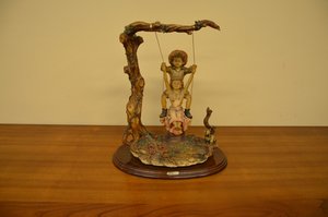 Soška dětí na houpačce u stromu s rustikálním podstavcem