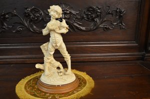 Soška chlapce s ptáčkem na ozdobném podstavci