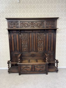 Velká tmavě mořená věšáková stěna se sedákem a bohatým řezbováním